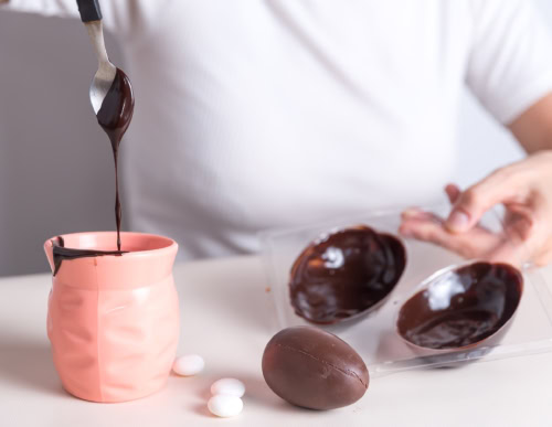 Como fazer ovo de Páscoa? Veja dicas para o preparo! 2 Homem preenchendo a forma de ovo de páscoa com chocolate.