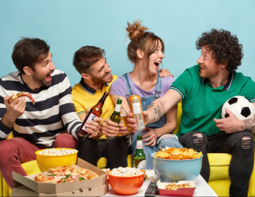 Petiscos para a Copa do Mundo: quais preparar antes de assistir aos jogos? 2 Grupo de amigos brindando em frente à mesa com petiscos.