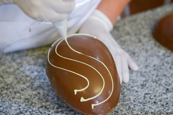 Como fazer ovo de Páscoa? Veja dicas para o preparo! 14 Ovo de chocolate sendo decorado com chocolate branco.